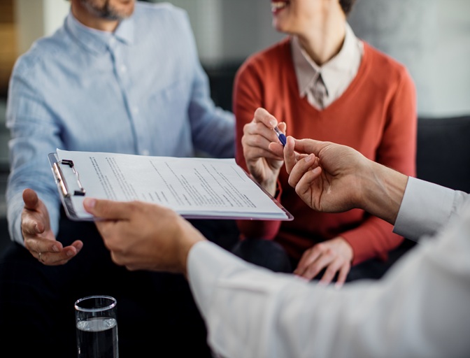 Home close up of unrecognizable couple signing a contract with financ